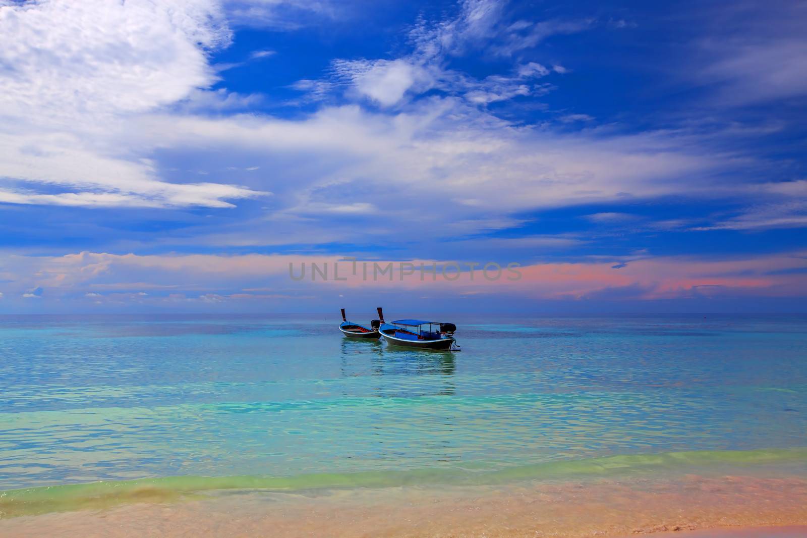 Sun setting over boats in the water on Koh Lipe