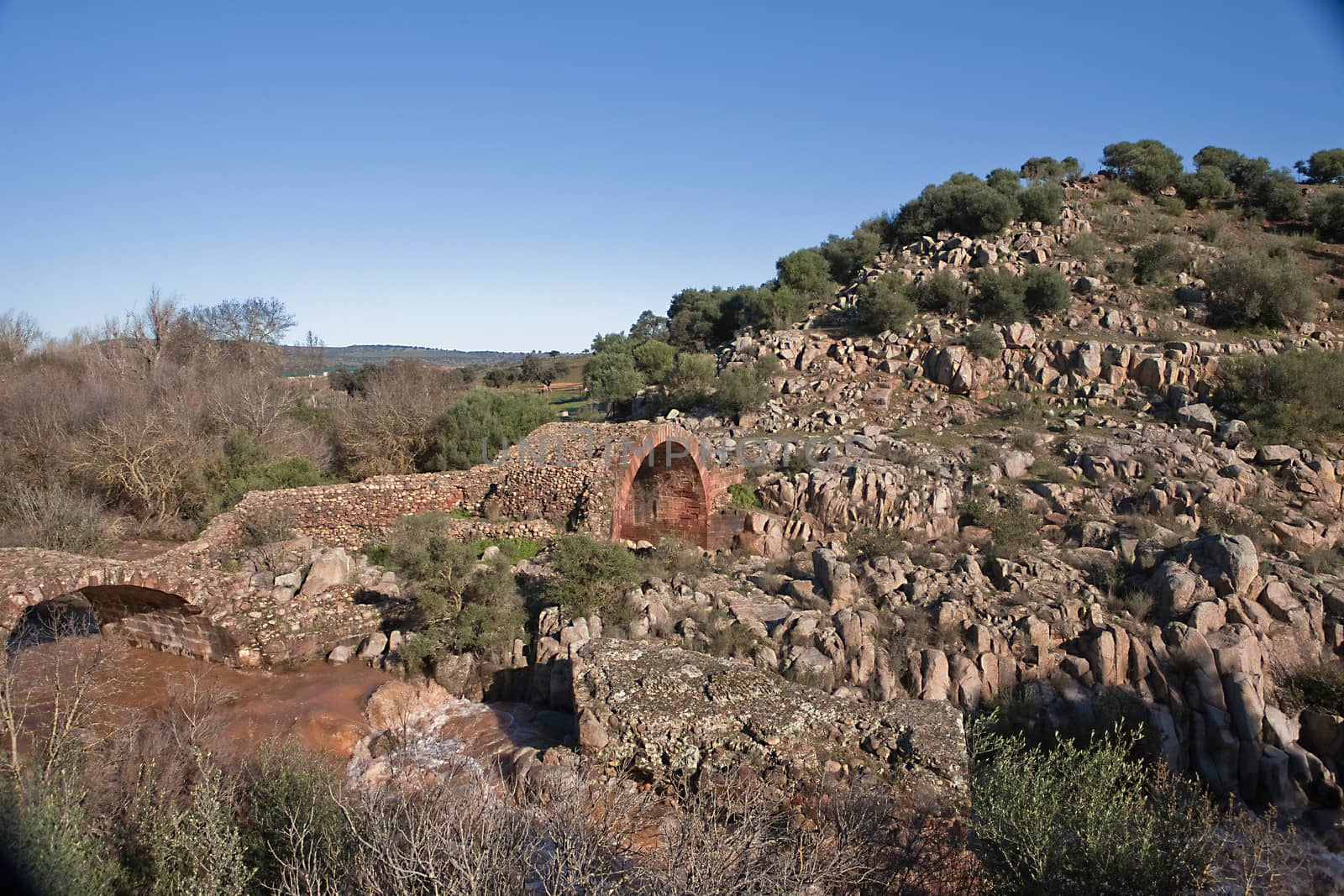 It is a Roman bridge that could belong to the primitive via Herculea, linking the ancient Oretania with the Spanish Levant, 3rd century a. d. C.. Is the landscape a beautiful formation of granitic rocks that are precipitating the River Guarrizas, forming two spectacular waterfalls that save the unevenness caused by the failure of Linares.