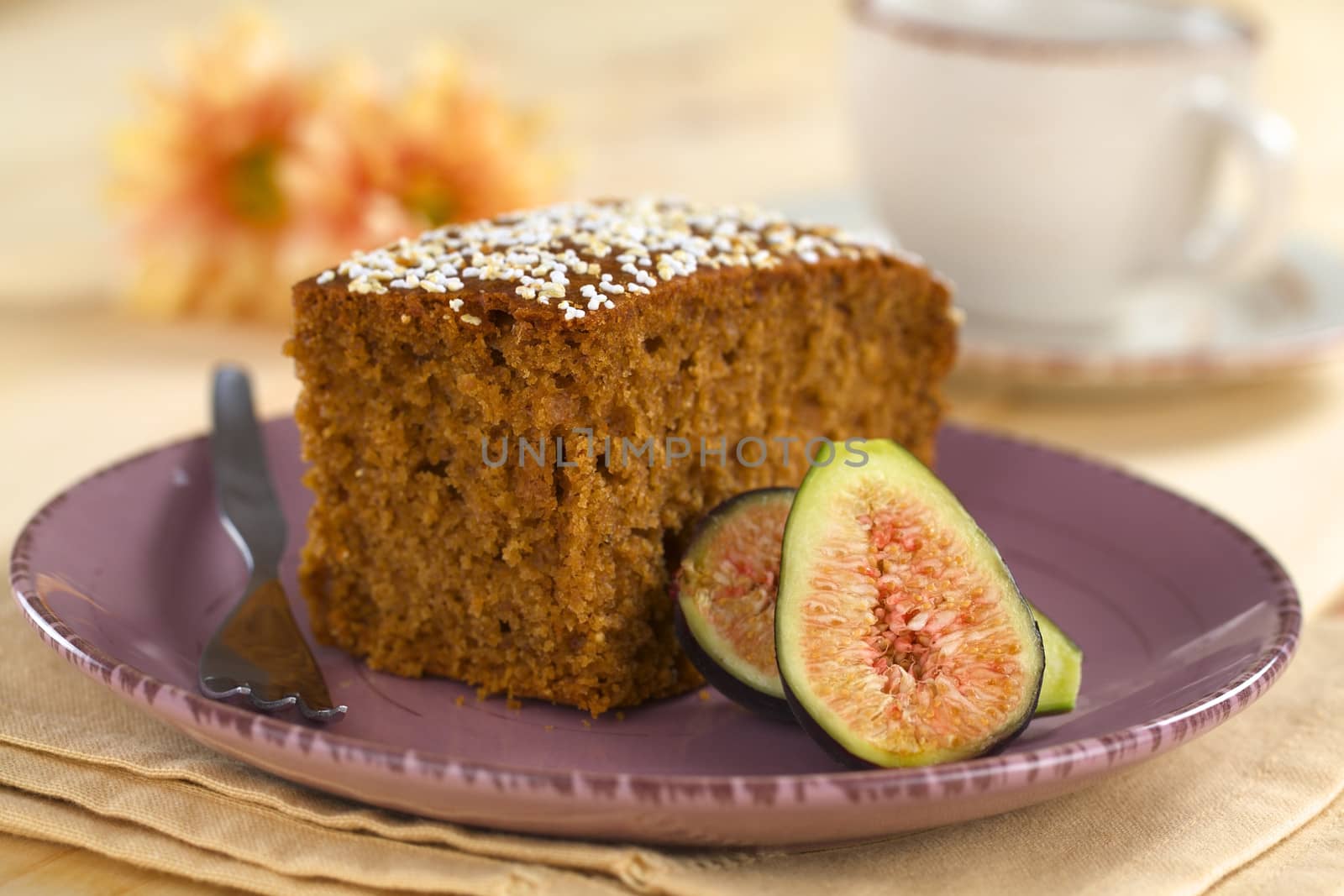 Fresh fig cake with fig halves on a purple plate with pastry fork (Selective Focus, Focus on the front upper corner of the cake and the middle of the fig half )