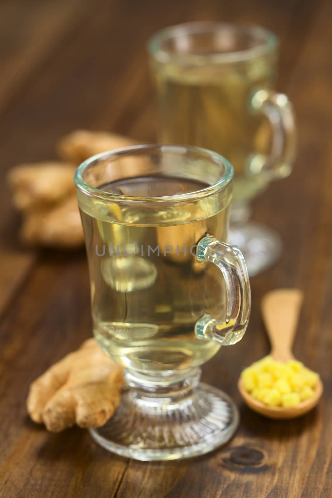 Freshly prepared hot ginger tea made of fresh ginger root served in glass (Selective Focus, Focus on the front of the rim and the handle of the glass)