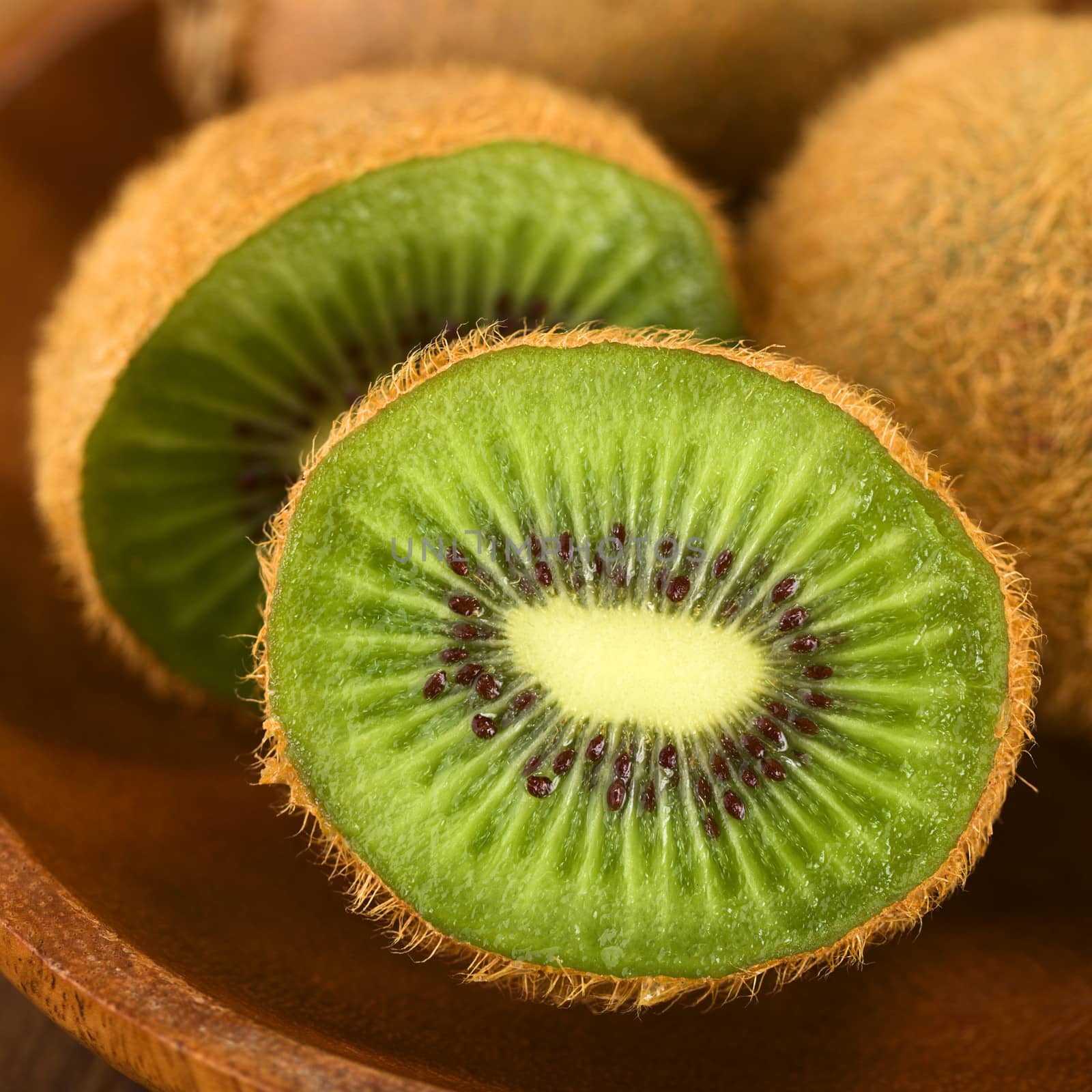Kiwi fruits on wooden plate (Selective Focus, Focus on the half kiwi)