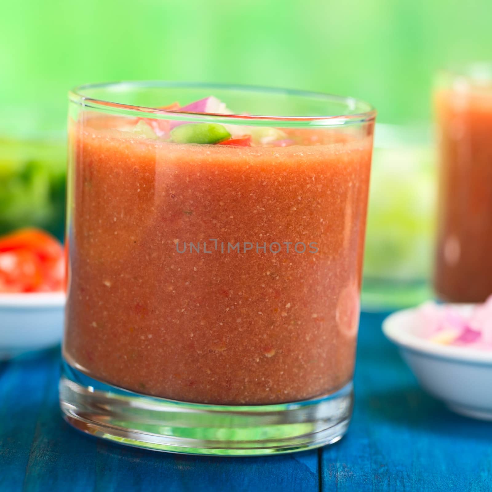 Traditional Spanish cold vegetable soup made of tomato, cucumber, bell pepper, onion, garlic and olive oil served in glass (Selective Focus, Focus on the front of the glass rim)