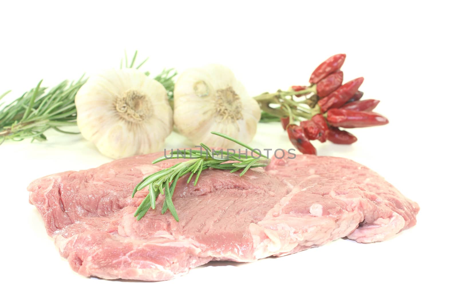 raw Ribeye steak with garlic and rosemary on a light background