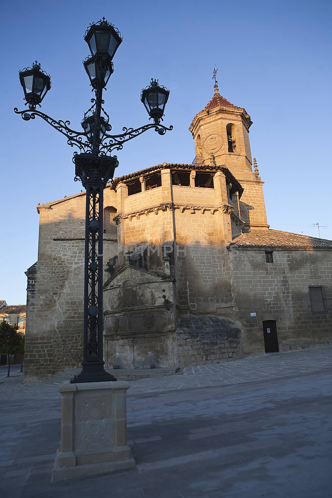 Sunrise in square on May 1, with side front and source of the church of San pablo and lamppost, Ubeda, Jaen province, Spain