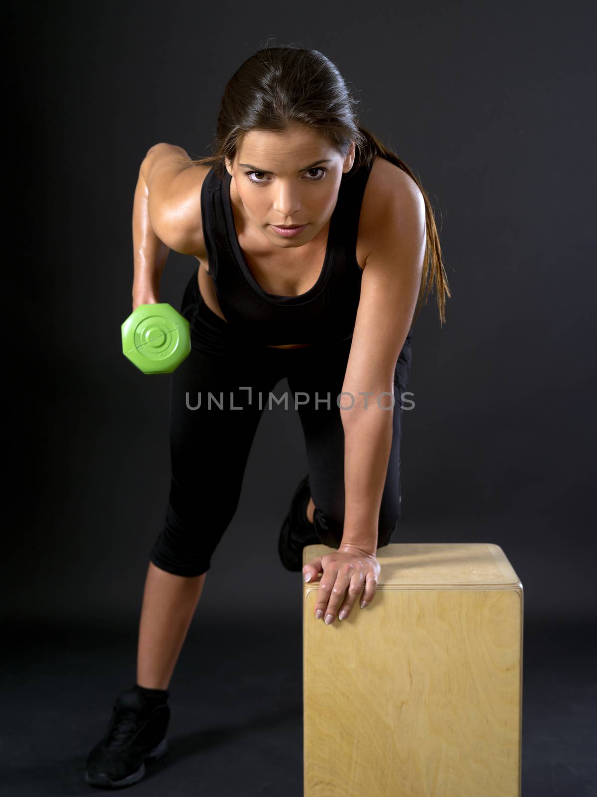 Photo of a beautiful brunette doing tricep extensions with a dumbbell.
