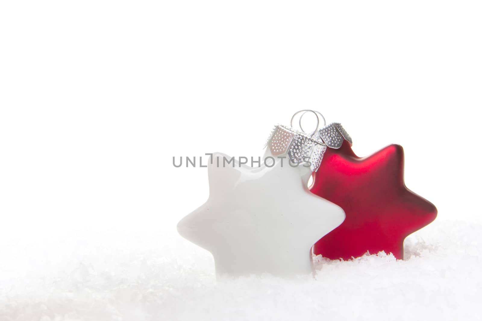 white and red christmas baubles as christmas star on snow 