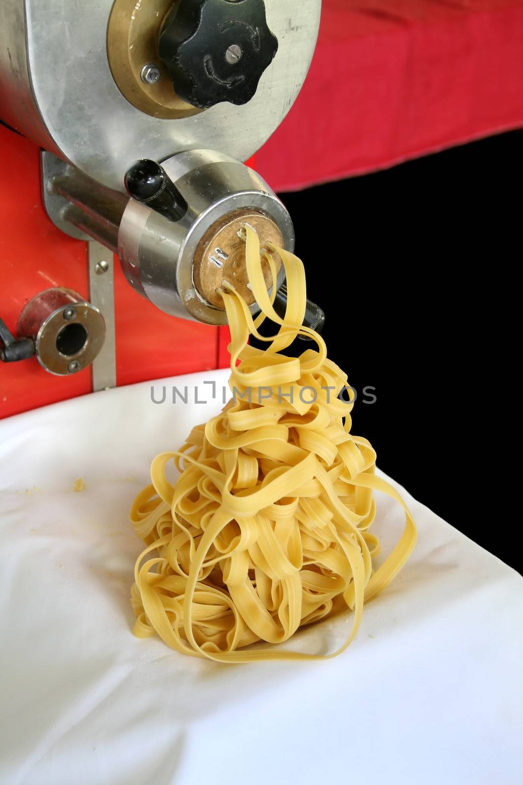 Pasta making machine turning out fettucini.