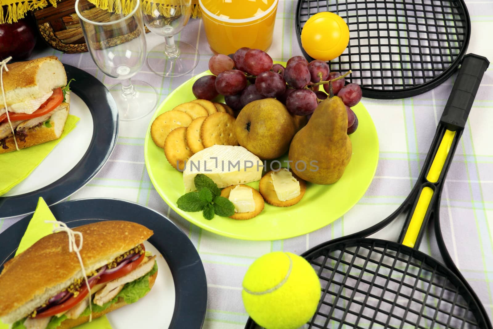 Fresh fruit and cheese laid out amongst a picnic spread.