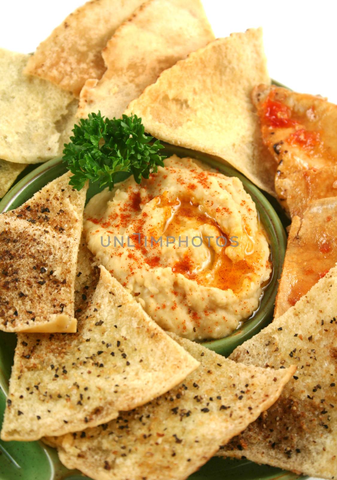Colorful and textured baked pita bread crisps with hommus dip.