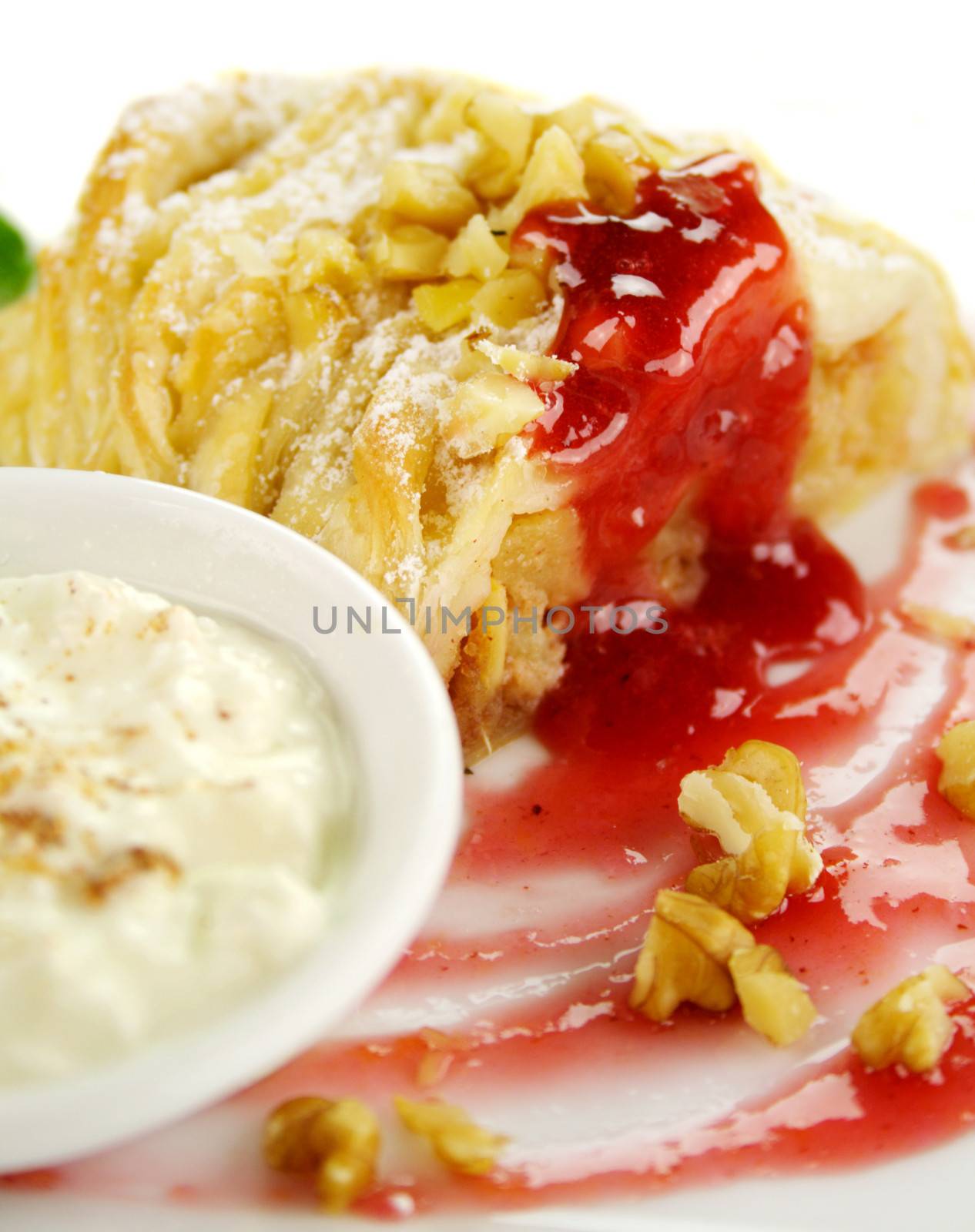 Delicious fresh baked plaited apple pie with raspberry sauce and walnuts ready to serve.