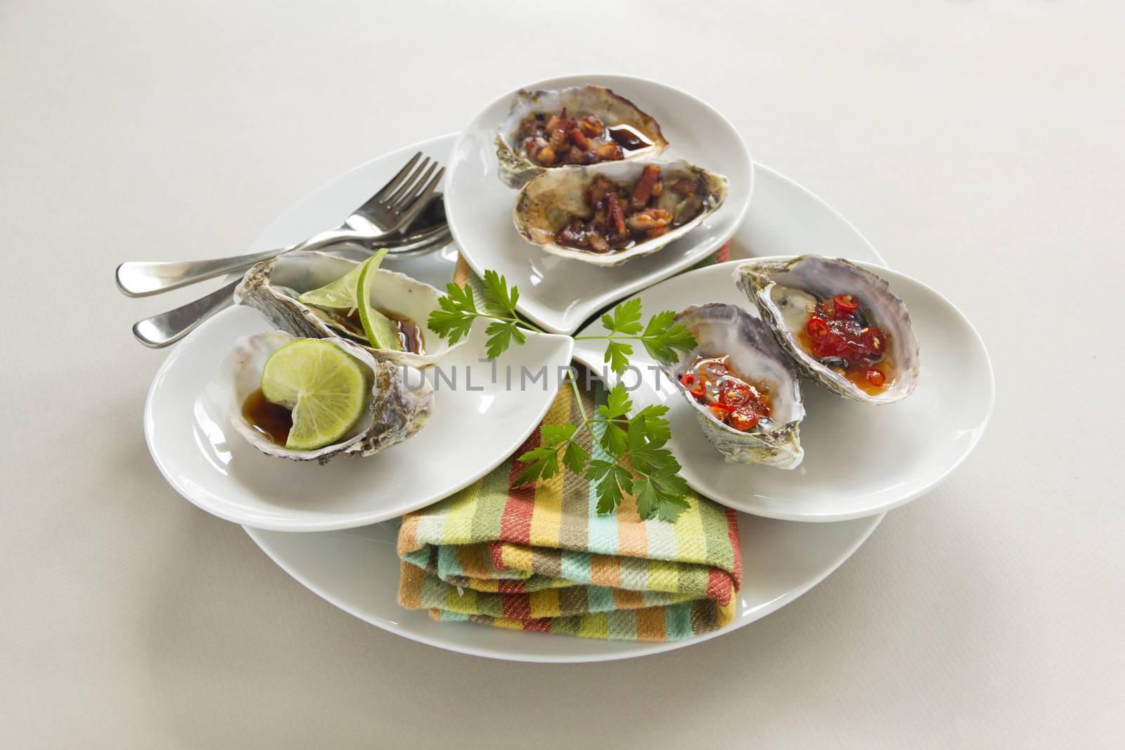 Platter of oysters including oysters kilpatrick, with sweet chilli and with lime and soy sauce.