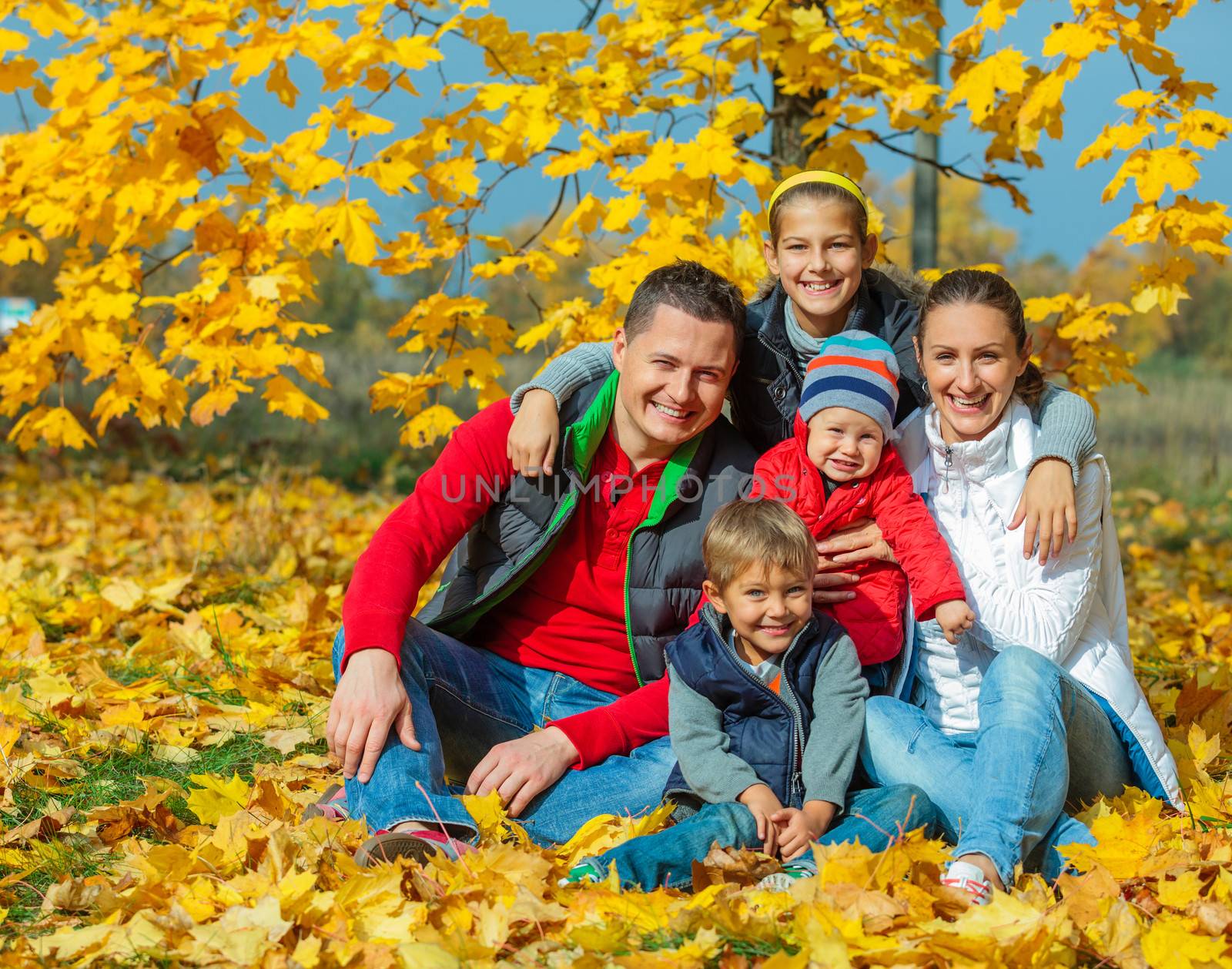 Happy family with three kids at beautiful autumn park
