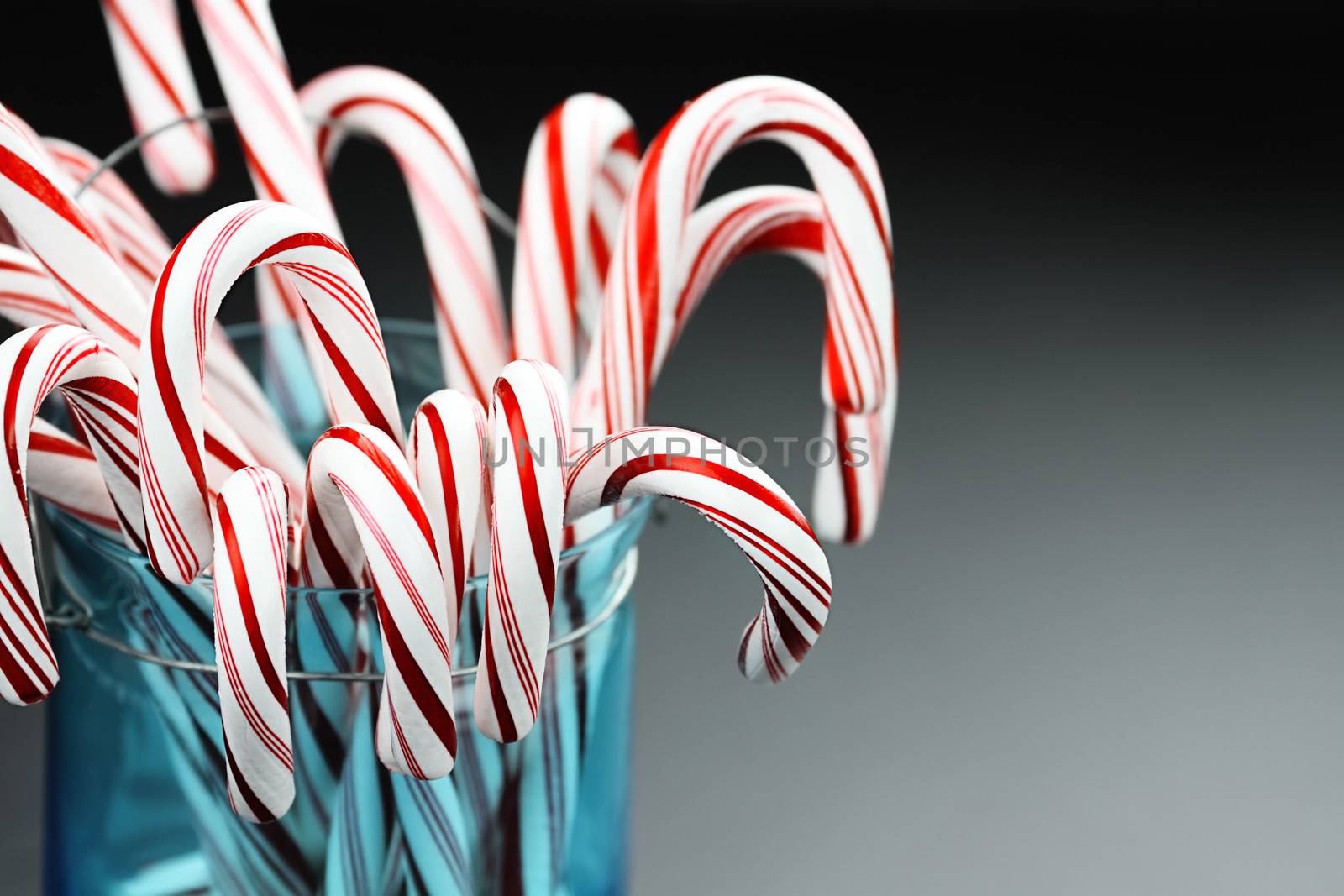 Jar of candy canes against a grey background with copy space.