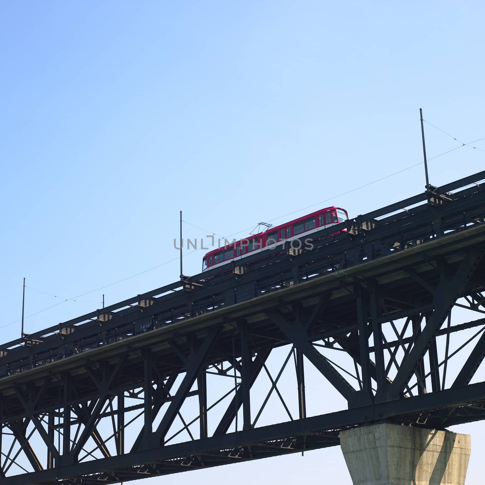Red trolley car on tracks against blue sky