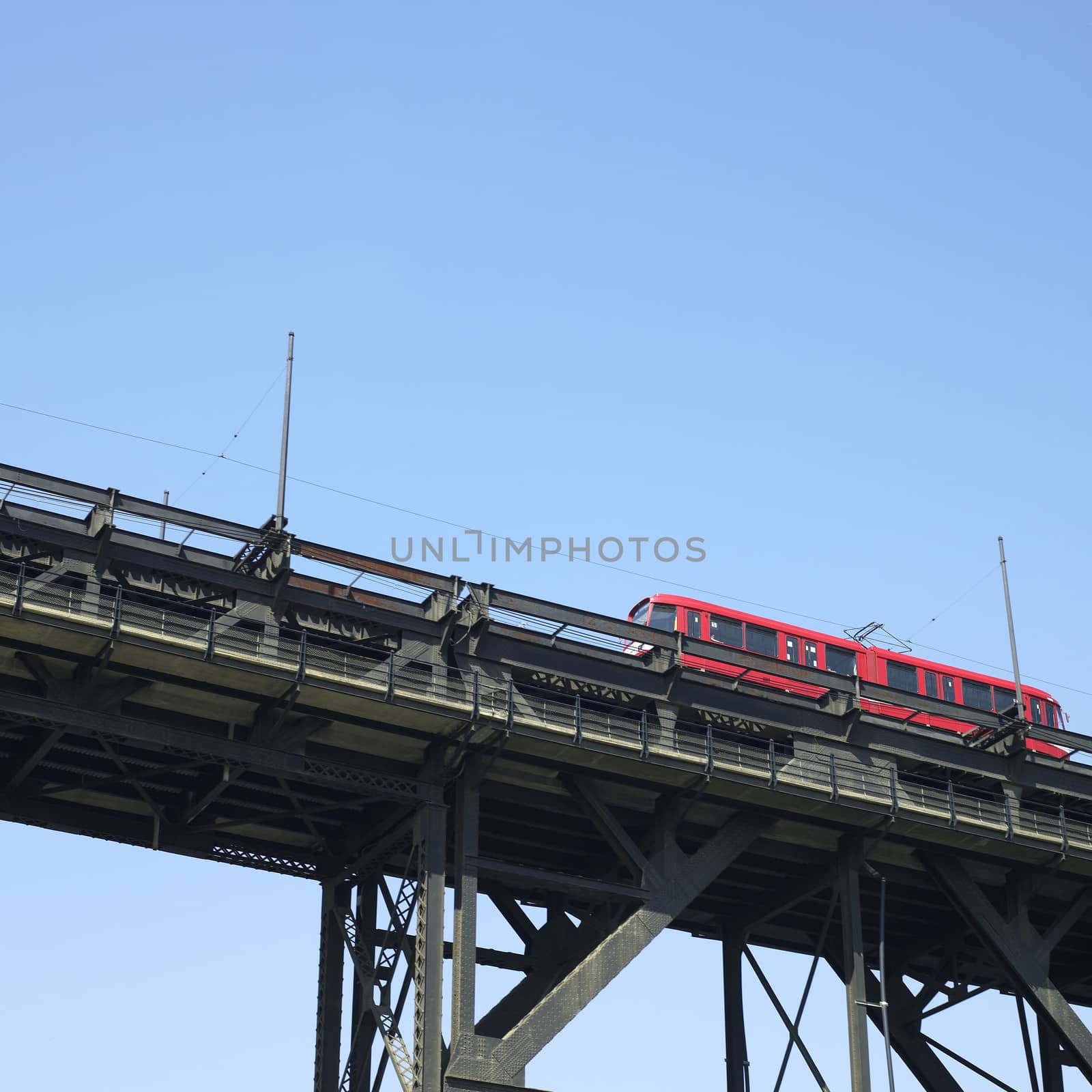 Red trolley car on tracks against blue sky