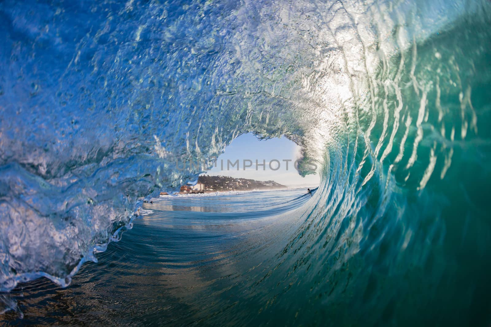 Water angle swimming inside hollow curling breaking wave in morning light.