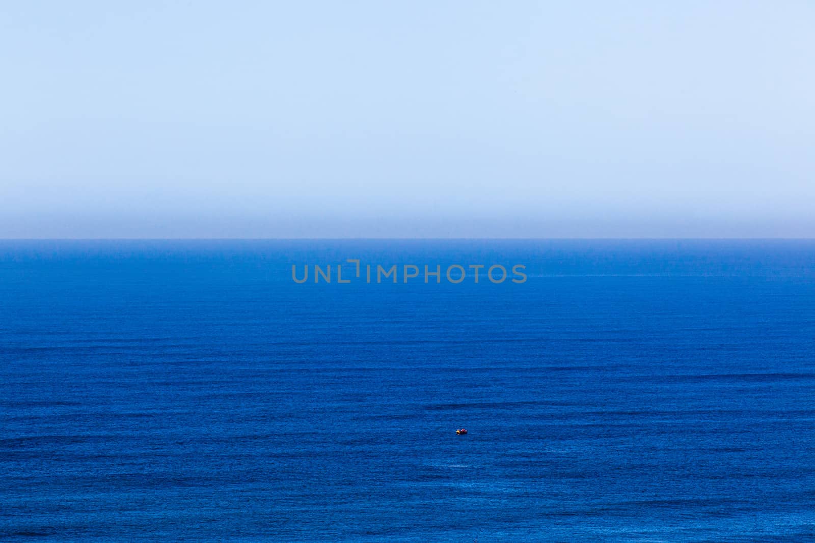 Clear blue ocean swells into blue distant horizon sky