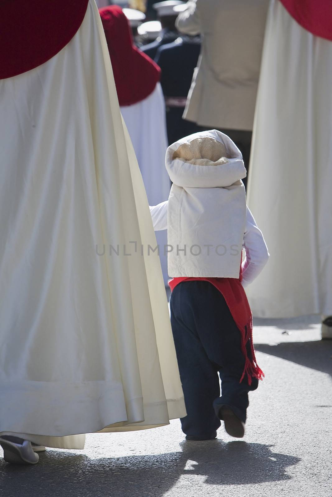 Boy dressed of costalero of his mother's hand during Holy Week, Spain
