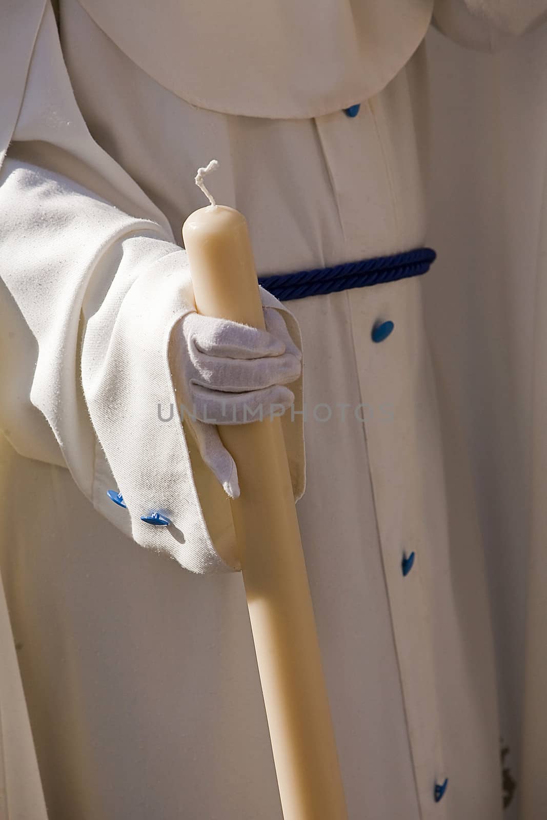 Detail penitent white holding a candle during Holy Week, Spain