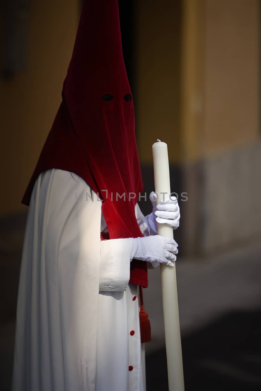 Detail penitent white holding a candle during Holy Week, Spain