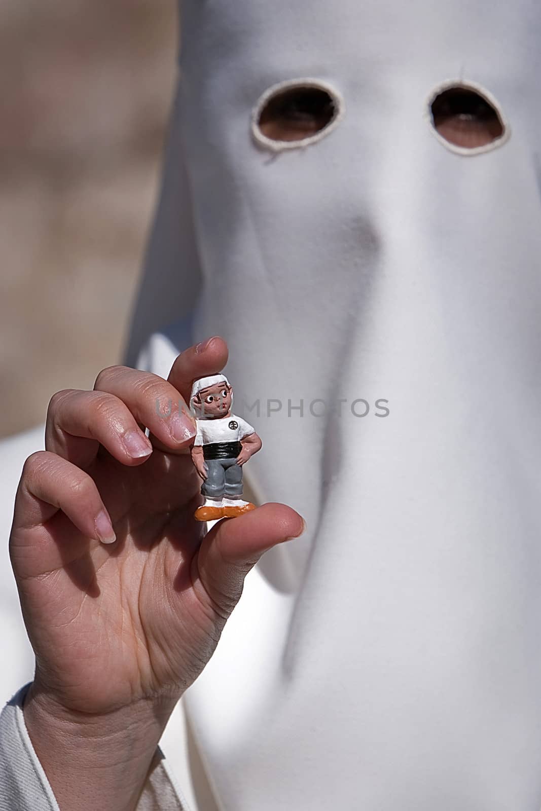 Penitent with a costalero figurine in his hand during Holy Week, Spain