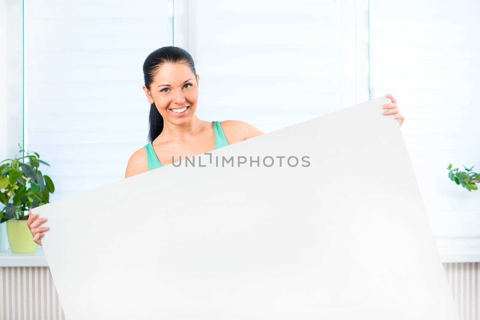 Portrait of happy young casual woman holding a blank signboard