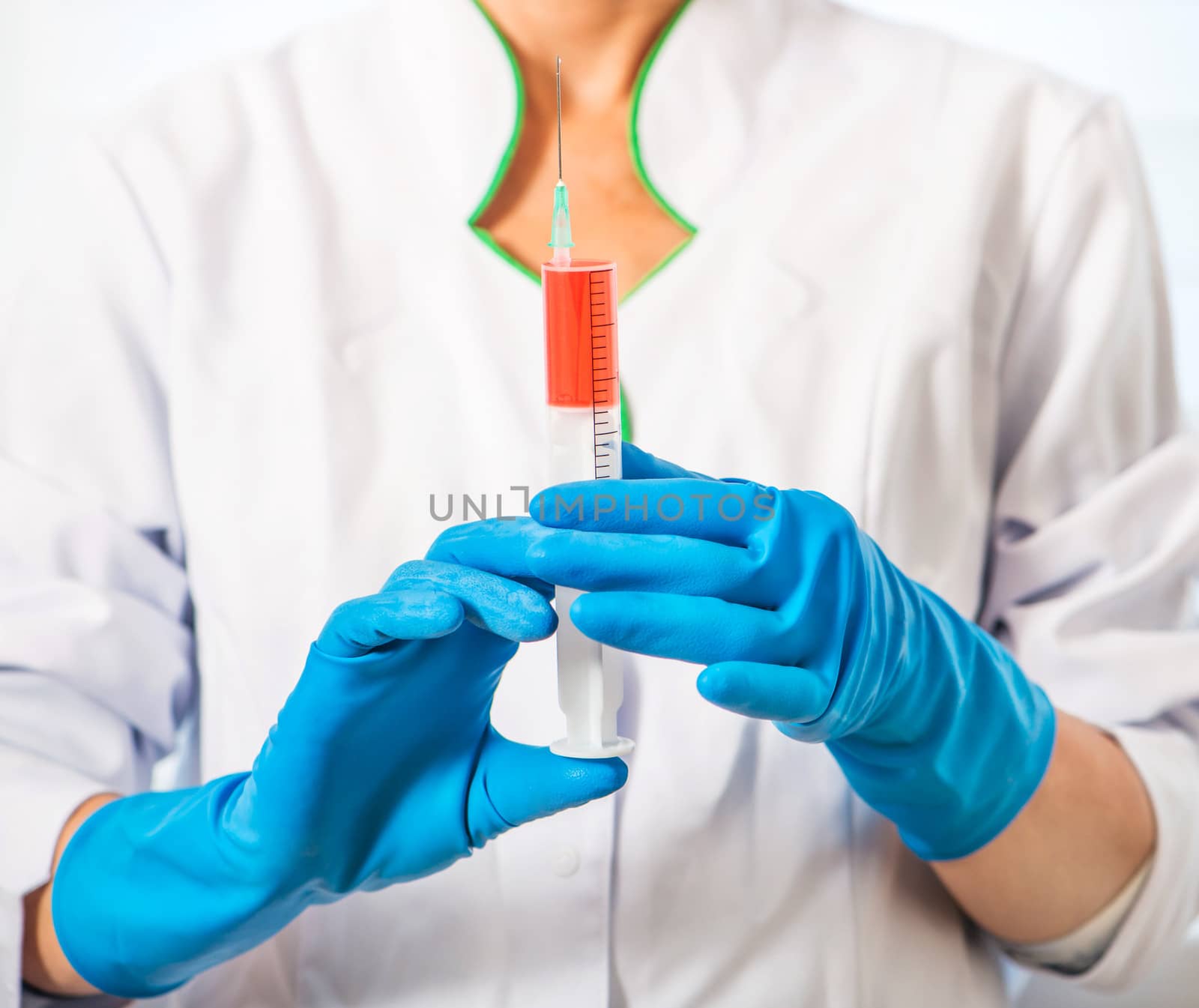 Doctor in blue gloves holding a syringe