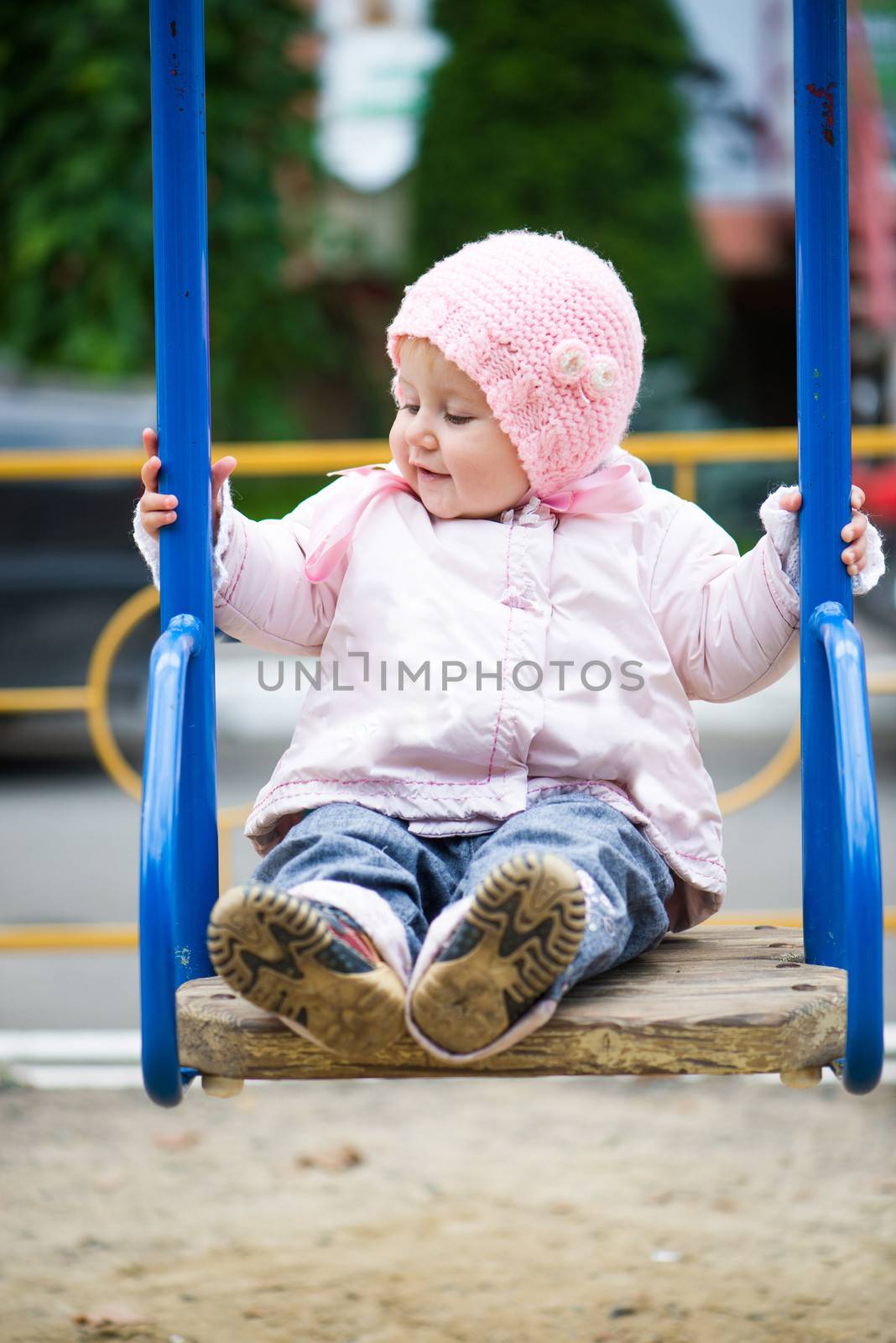 smiling little baby girl in a swing at the park