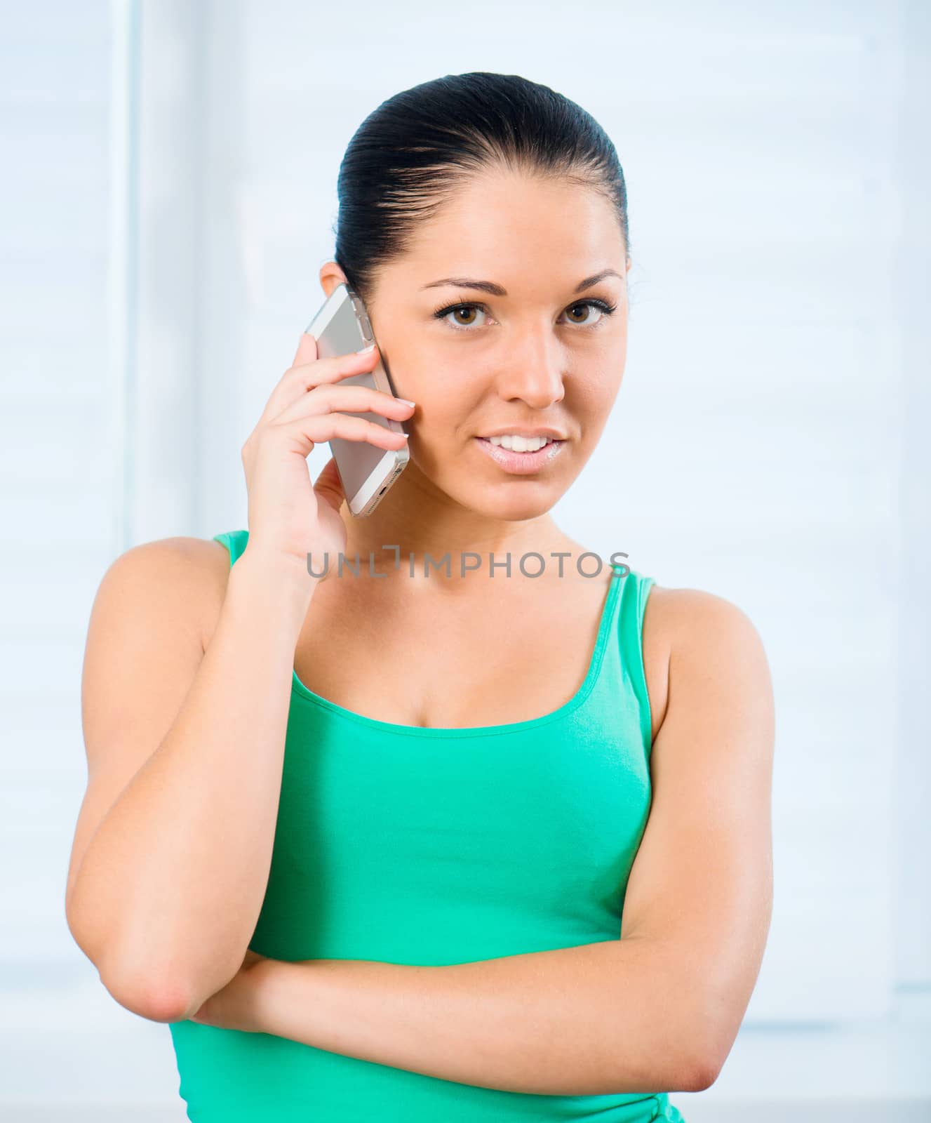 young smiling brunette woman talking by the phone at home