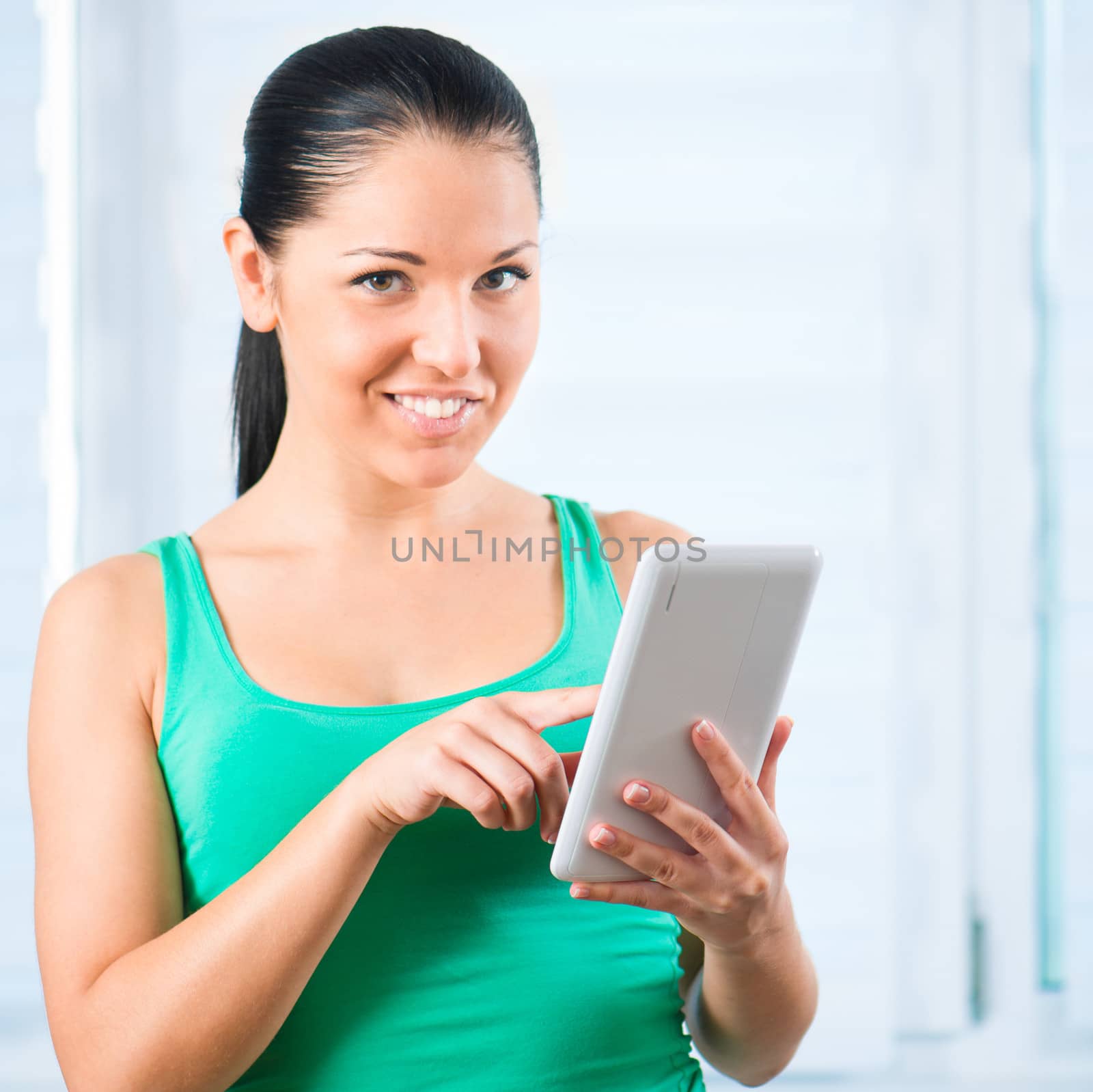 young smiling brunette woman holding a white TouchPad and looking at camera