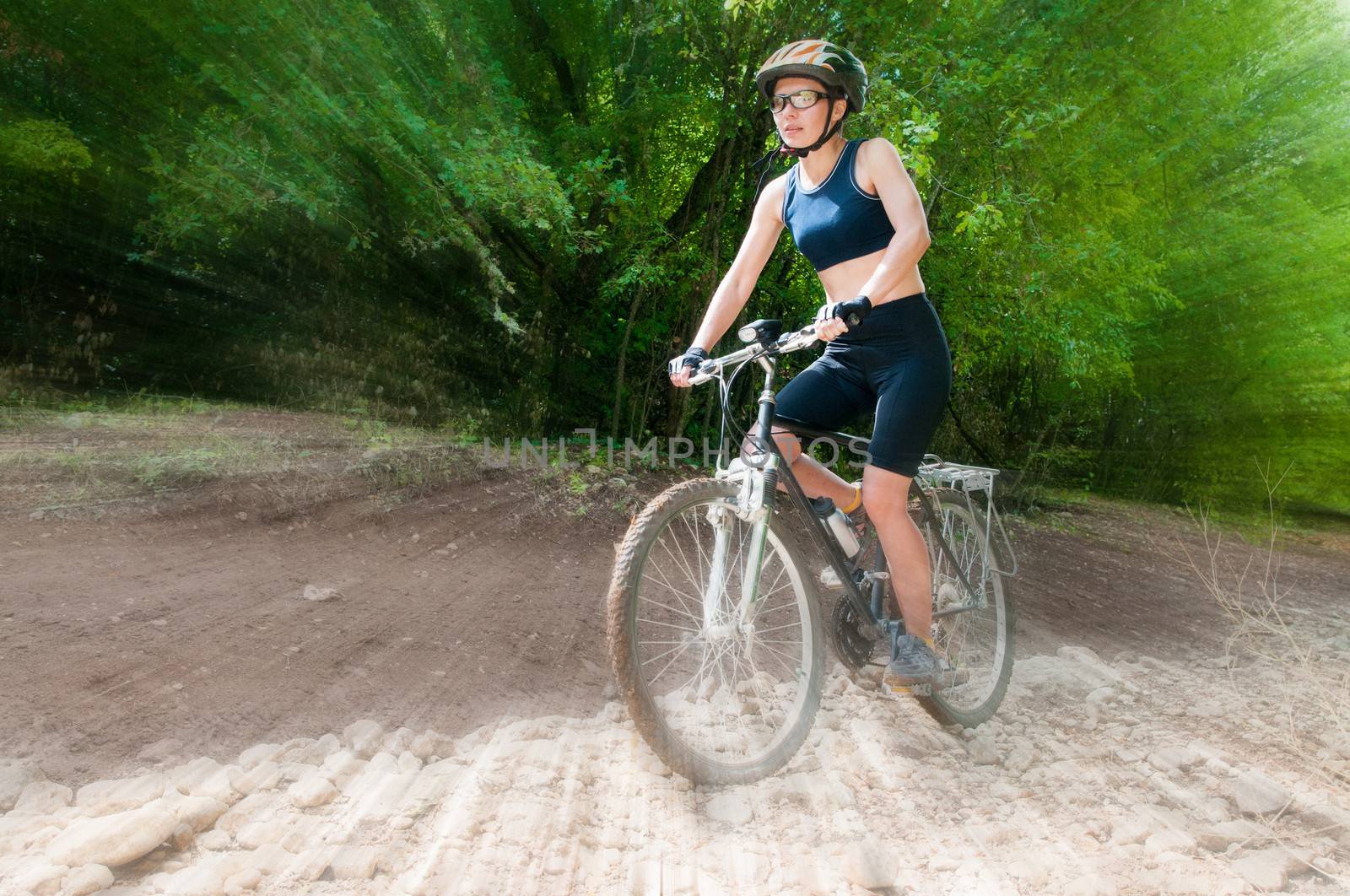 Female Cyclist rides through the forest with blur background