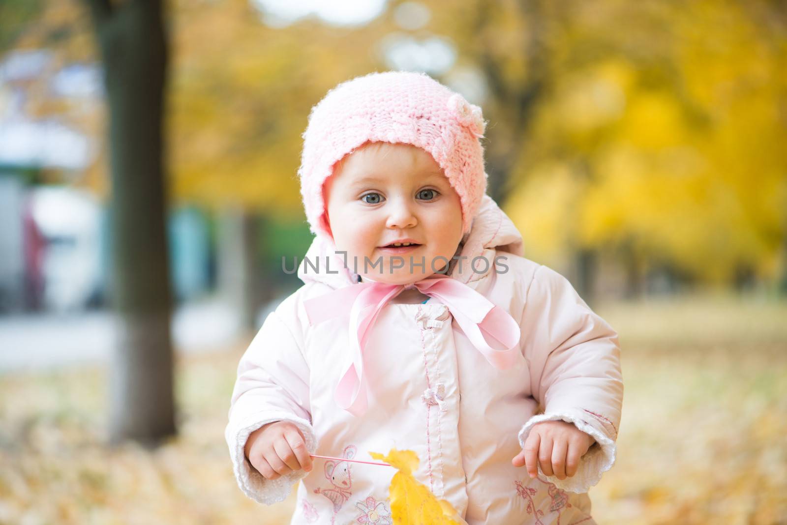 smiling little baby in the park with autumn leaves