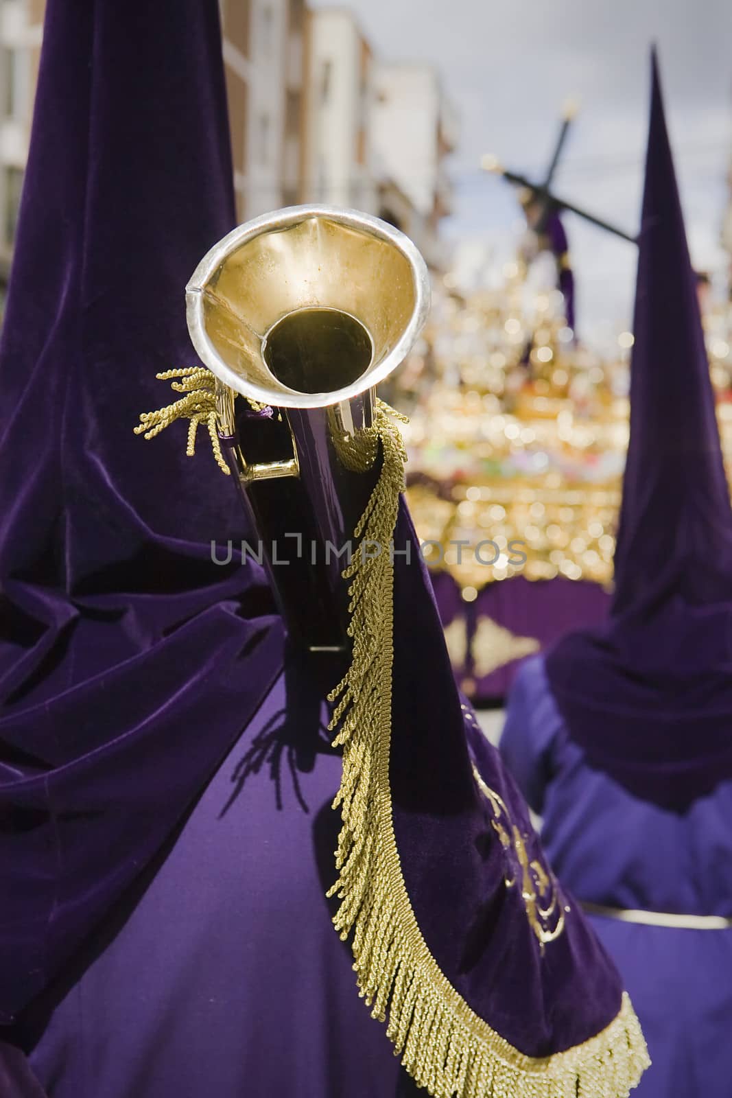 penitent purple tunic holds a trumpet during Holy week procession, Spain