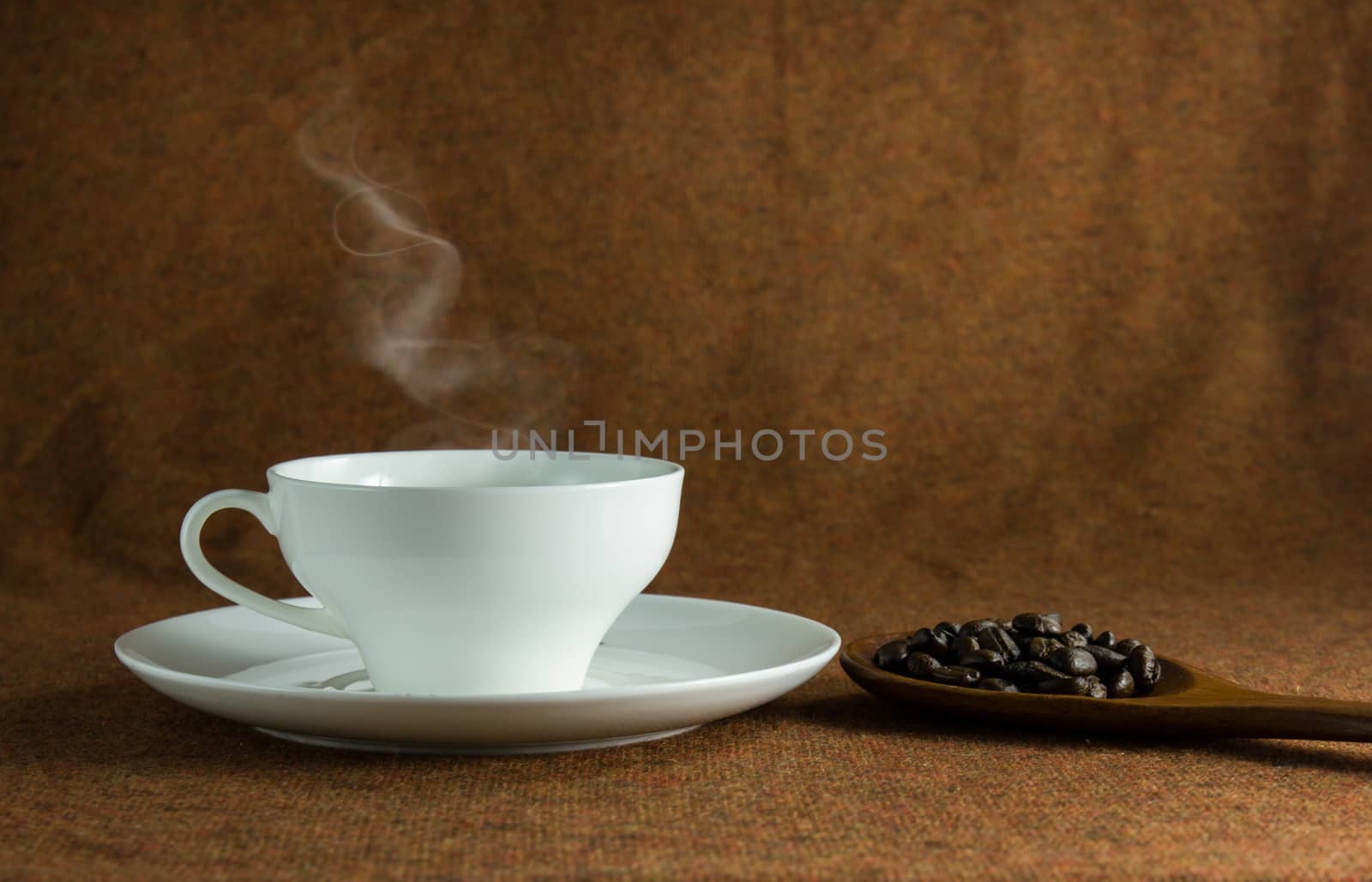 coffee cup and a spoon of baens still life on brown background.