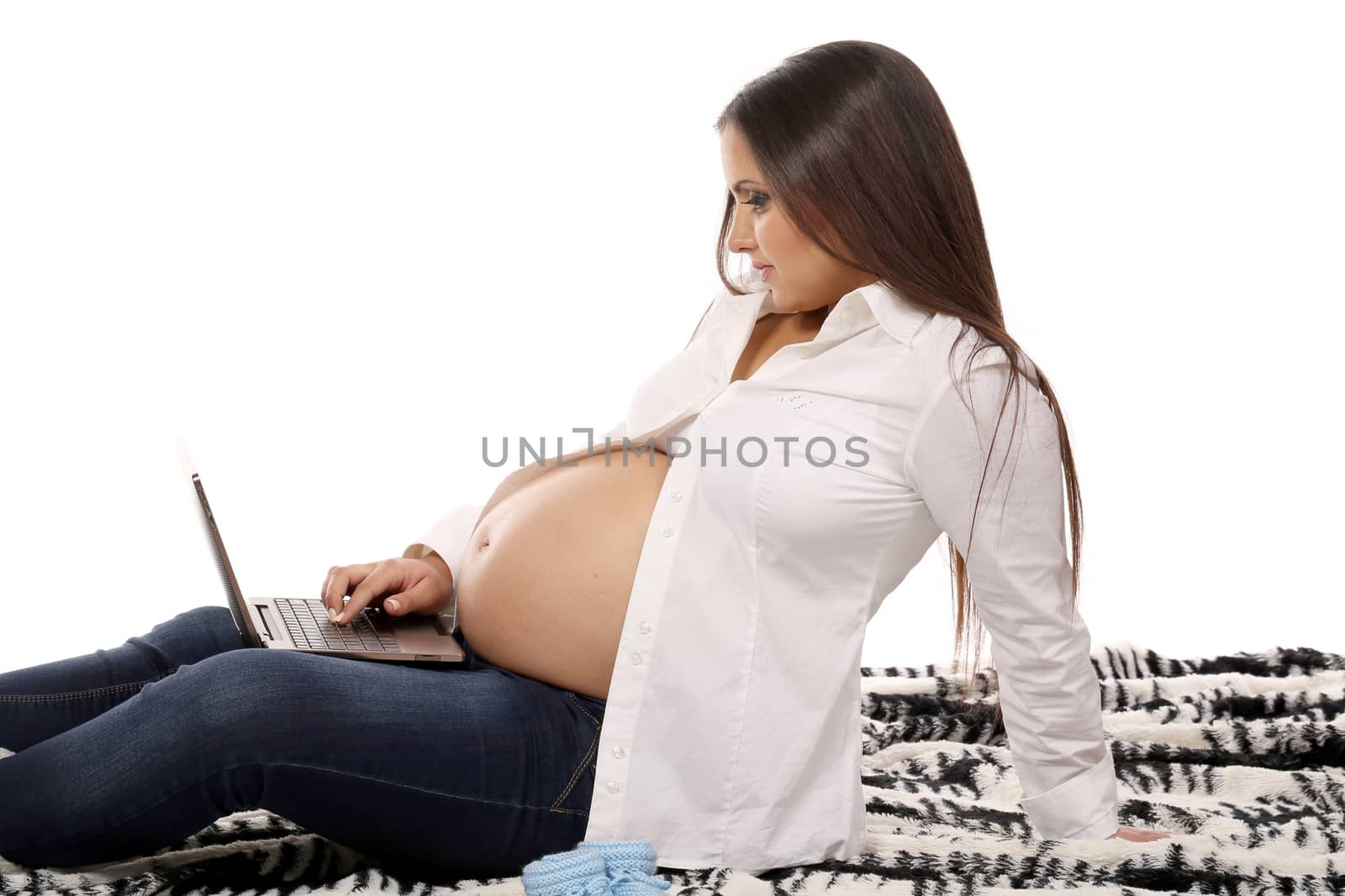 Young pregnant girl on the blanket with laptop. There is space for text