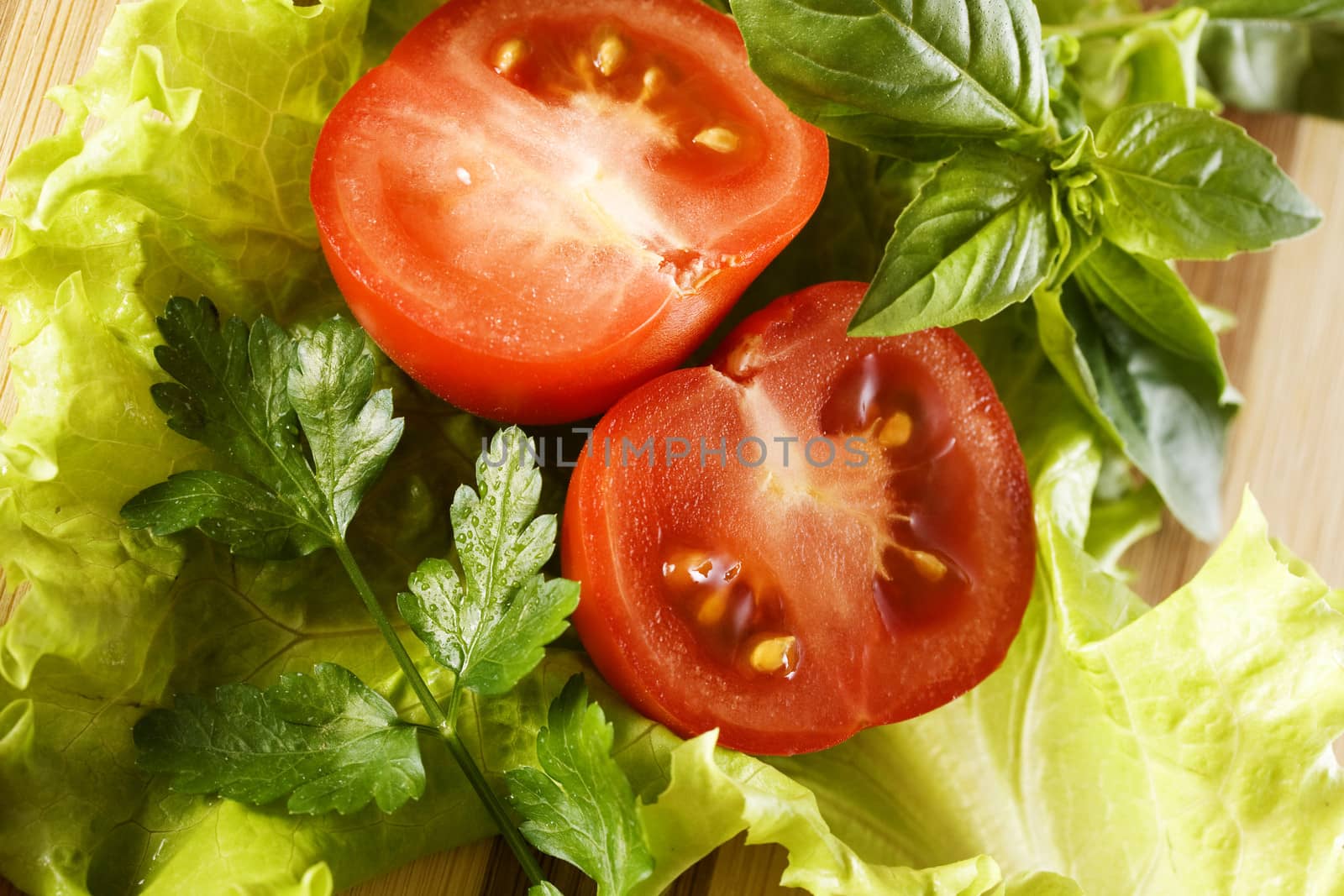 Sliced ??tomato, lettuce, basil and parsley. Preparation of salad.