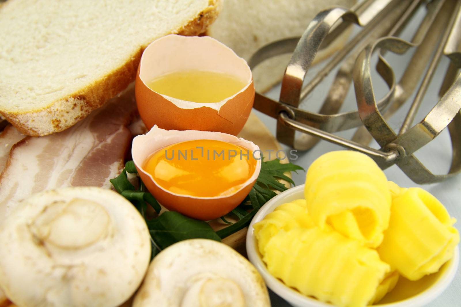 Bread, bacon, eggs, butter with toast ready to be cooked for an omelette.