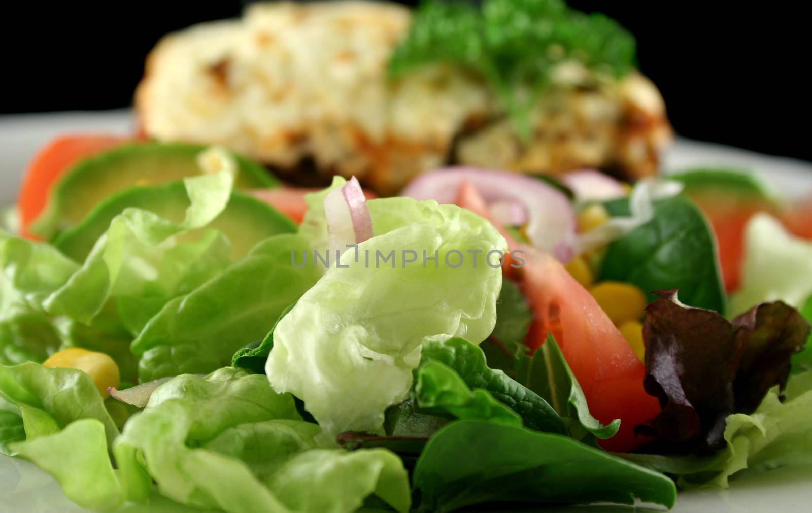Fresh tossed salad with moussaka in the background.