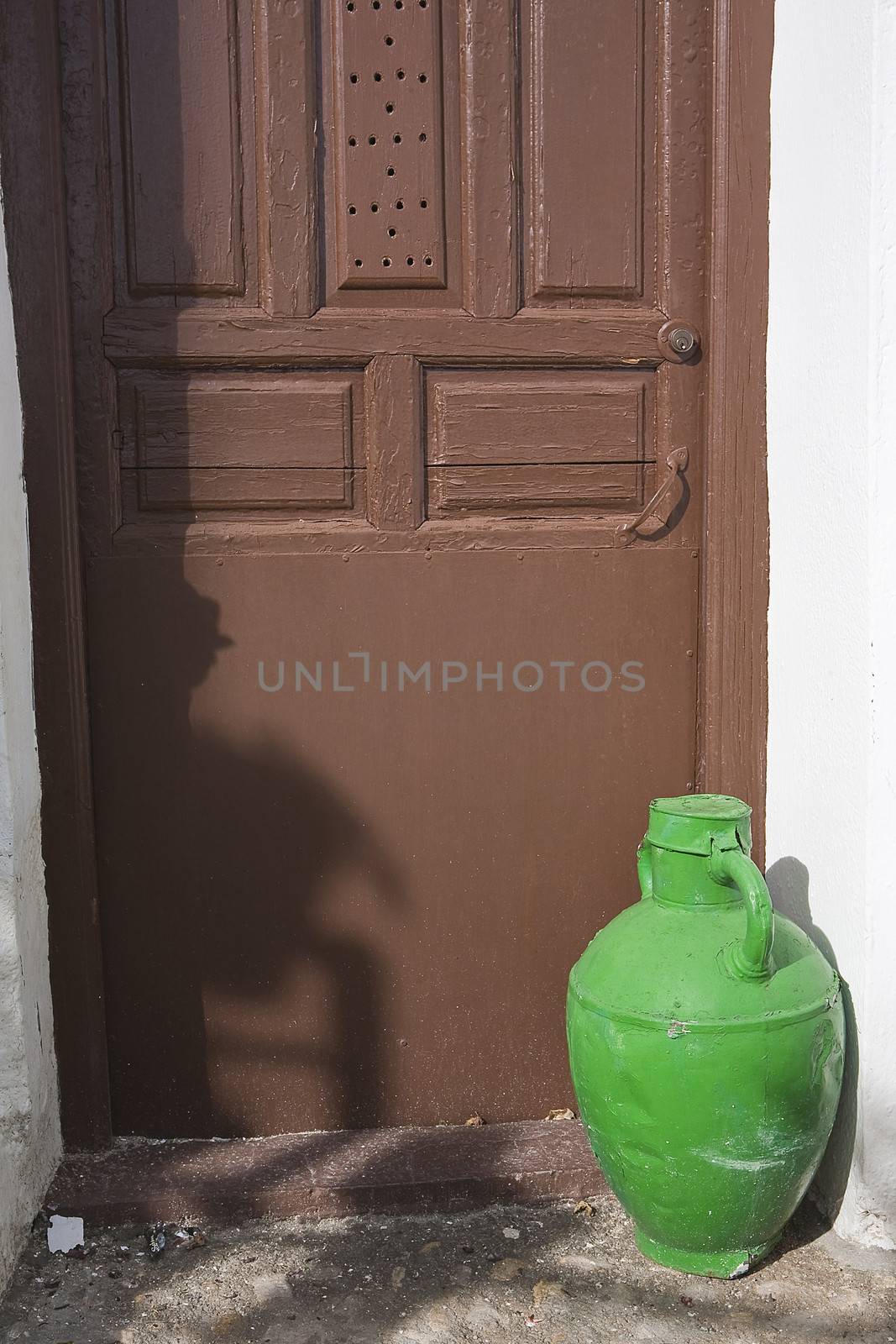 Old door of a house and a jar of green brass in Iznajar, Cordoba province, Andalucia, Spain