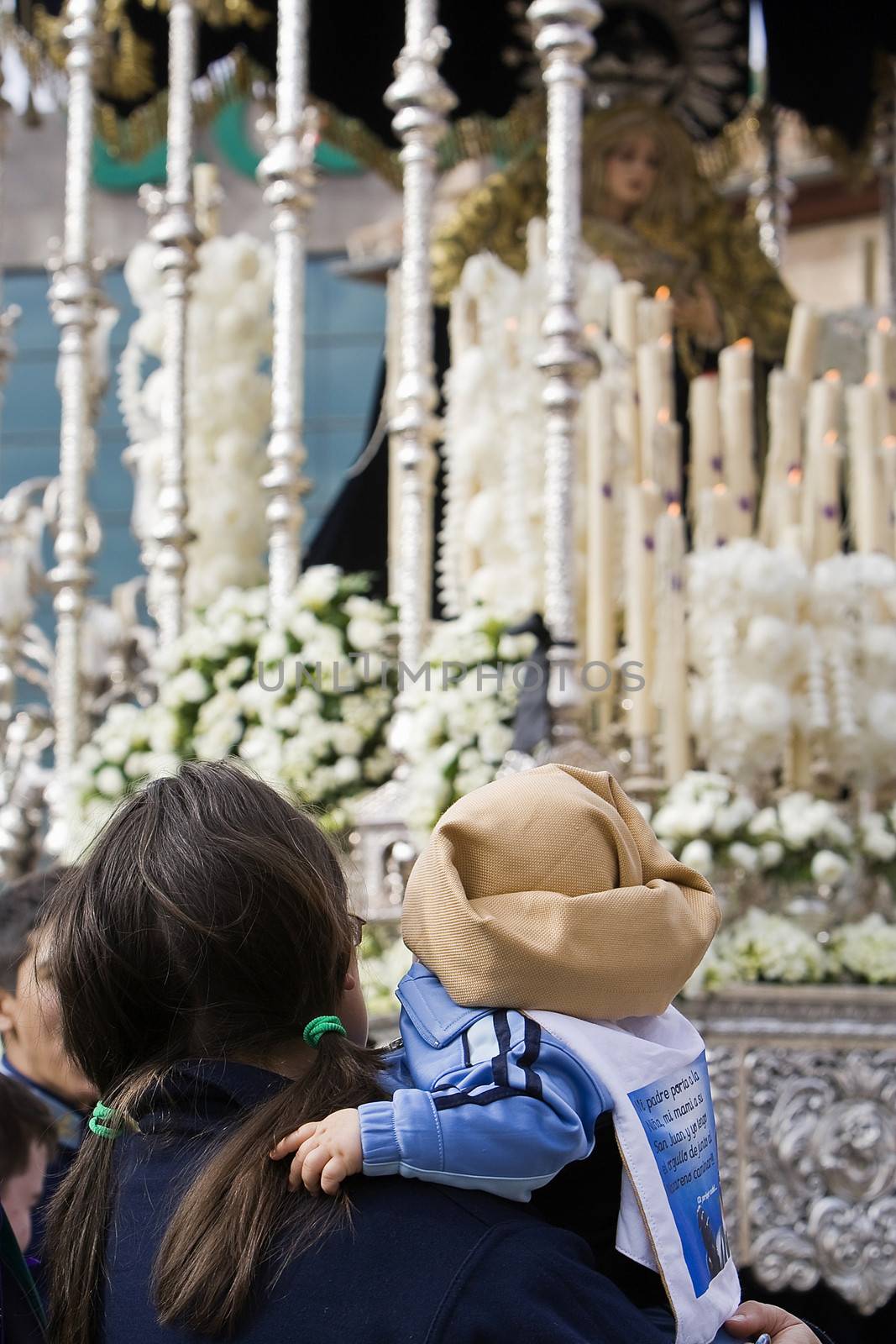 Women with a child in his arms costalero clothing in a procession of holy week, Andalucia, Spain