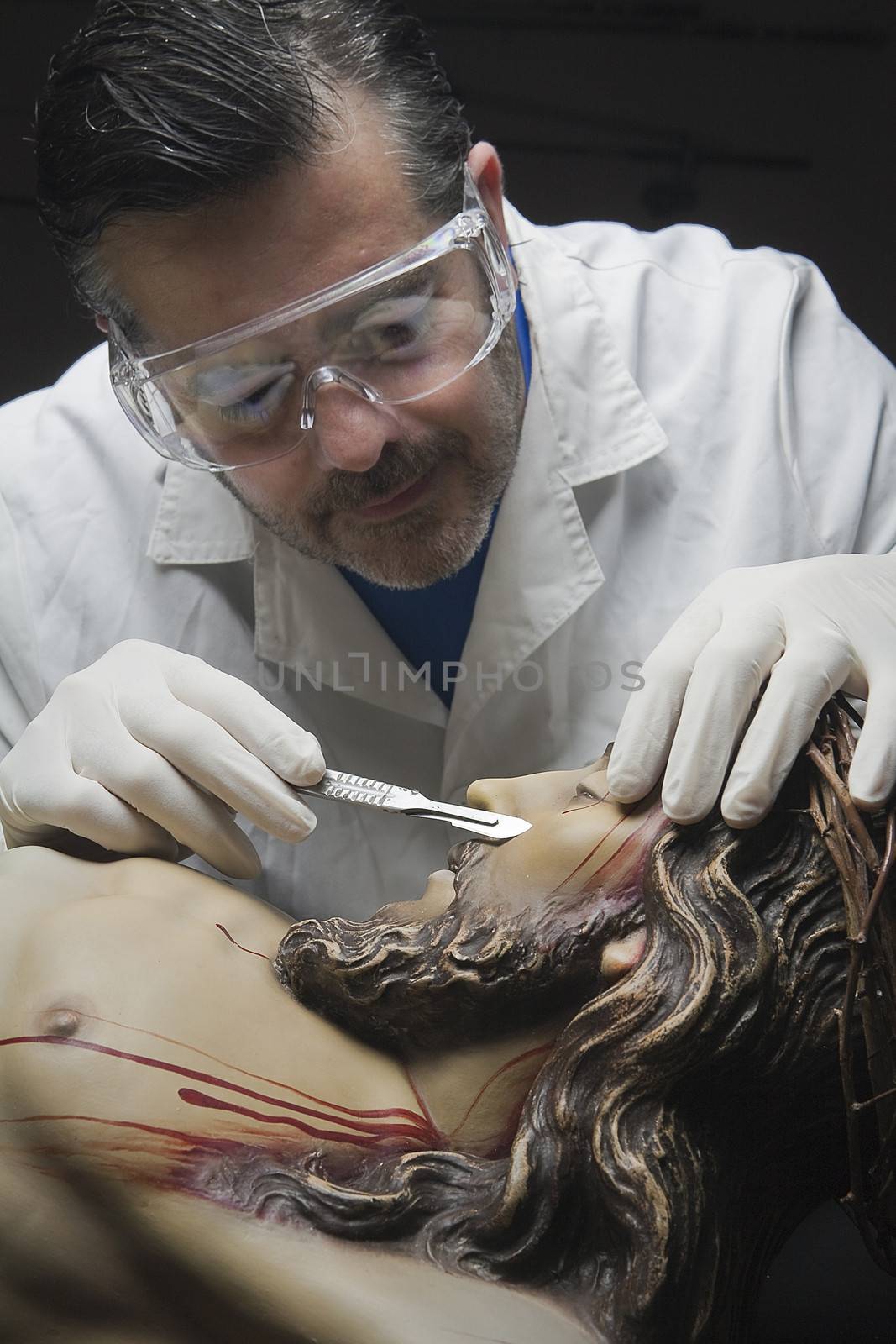 Professional Restorer with a scalpel repairing a sculpture of the crucified Christ, Andalusia, Spain