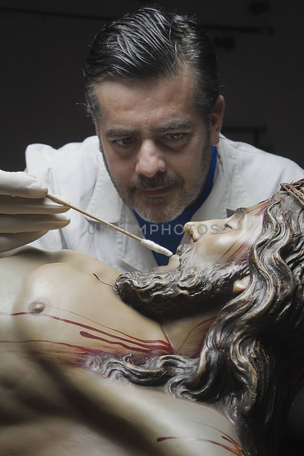 Cleaning of the face of a wooden sculpture of Christ crucified with an isopo impregnated with dimethylformamide, Andalusia, Spain