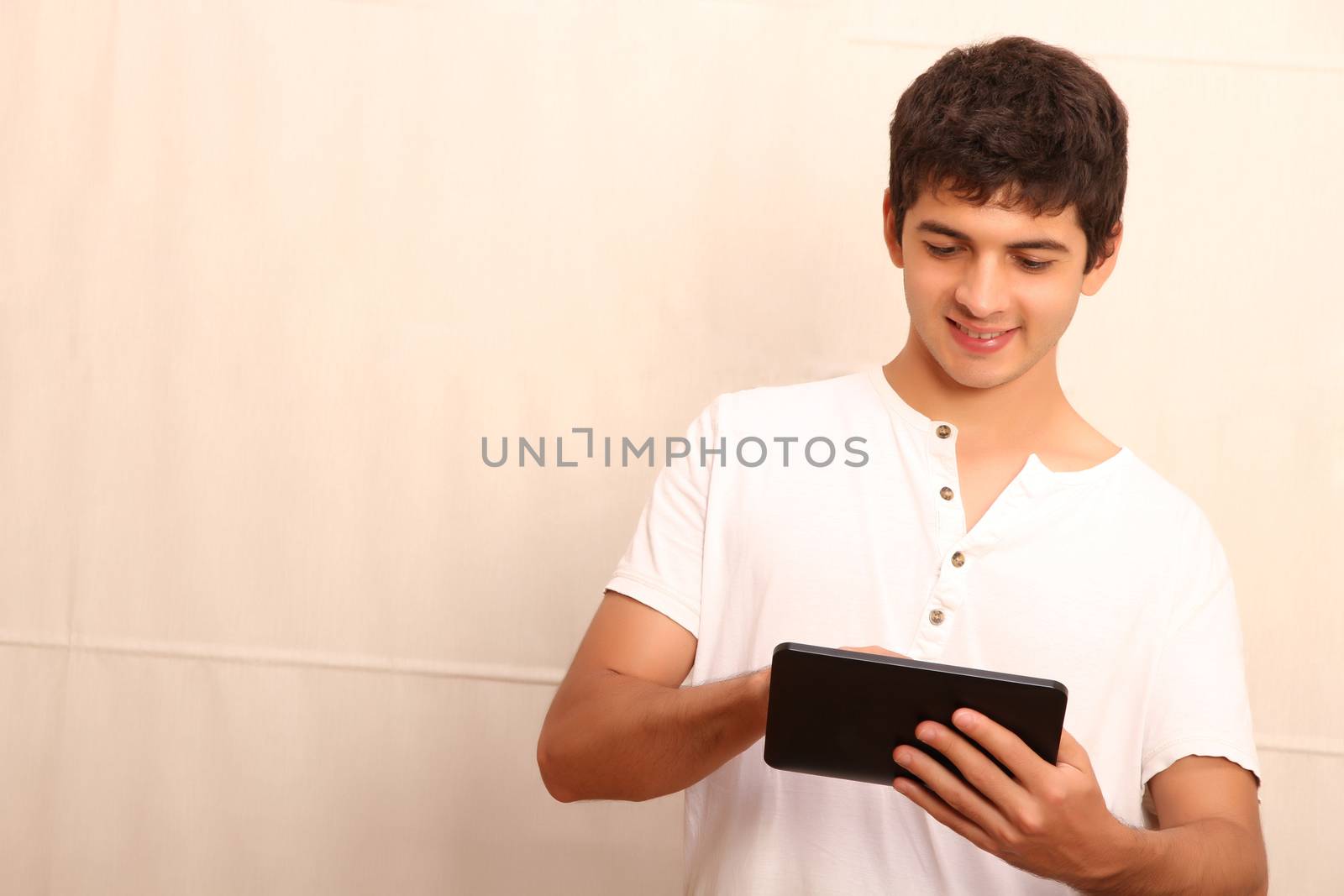 A young, latin man playing with a Tablet PC, face in focus
