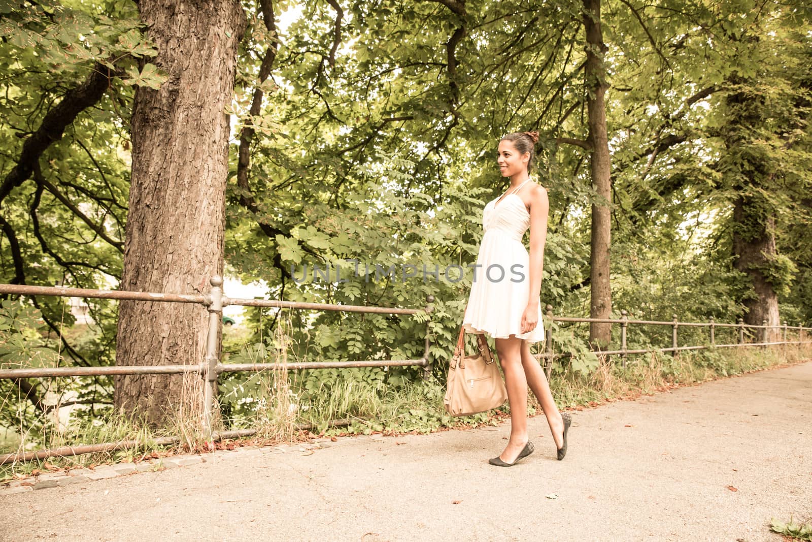 A young Girl walking in the park with her handbag.