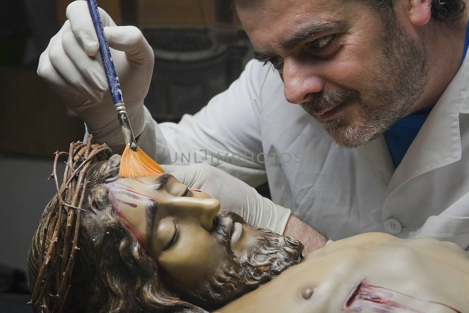 Cleaning of the face of a wooden sculpture of Christ crucified with a fan brush, Andalusia, Spain