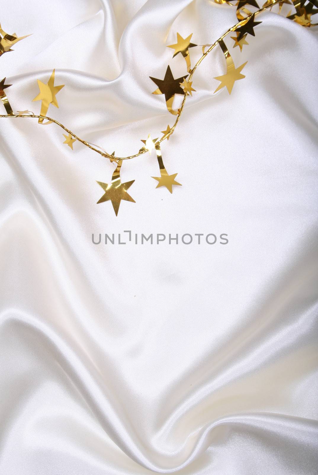 Golden stars and spangles on white silk as background