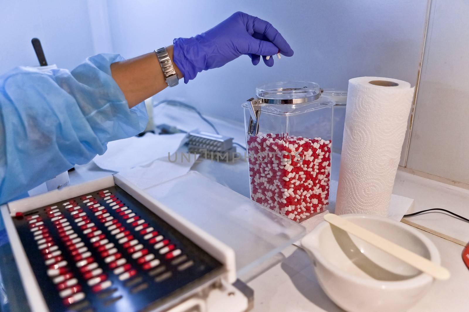 Packing white and red capsules in a sorting machine in a pharmaceutical laboratory, Spain