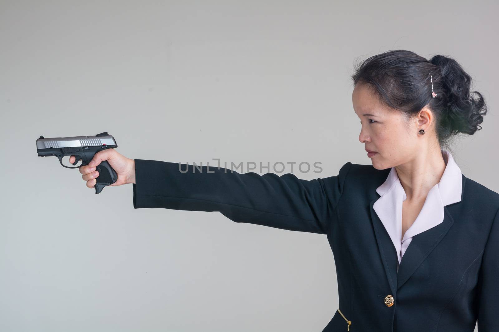 Woman aiming a hand gun by IVYPHOTOS