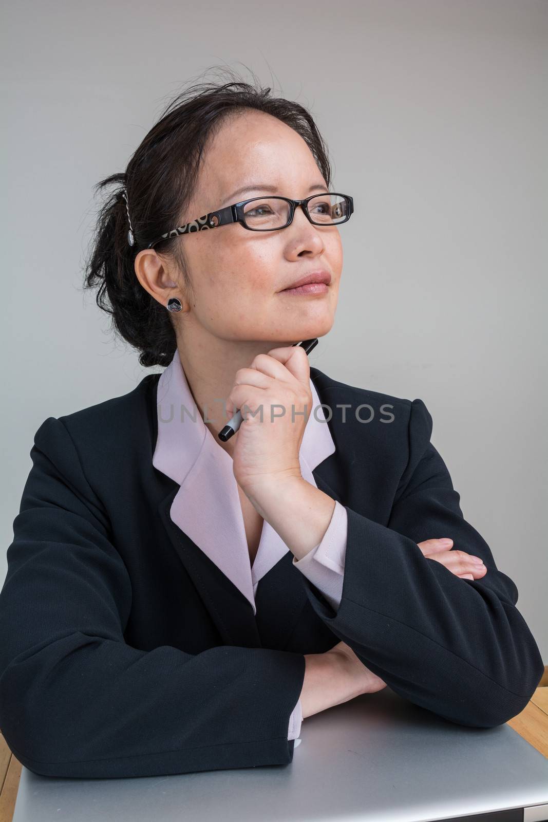 Professional woman in business suit with a closed laptop on desk