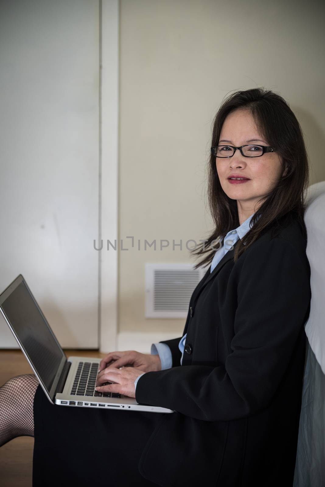 Woman with laptop sitting on floor by IVYPHOTOS